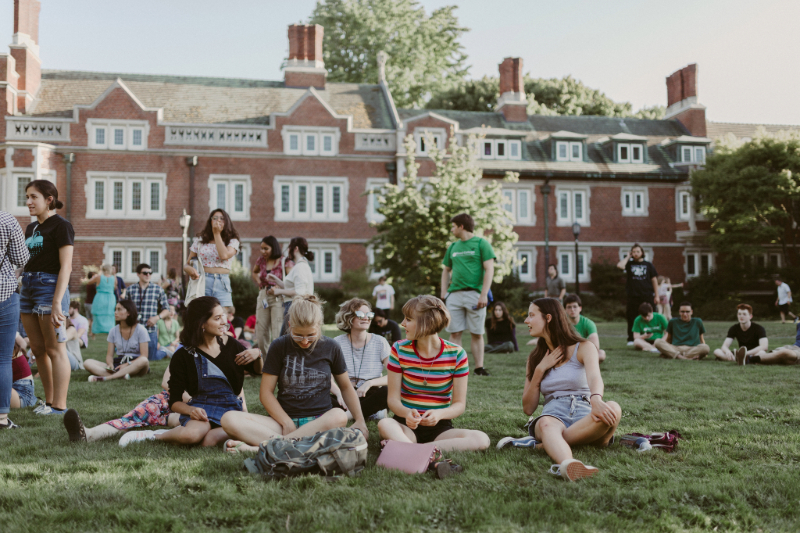 Group of students sitting down on the grass at Reed and talking