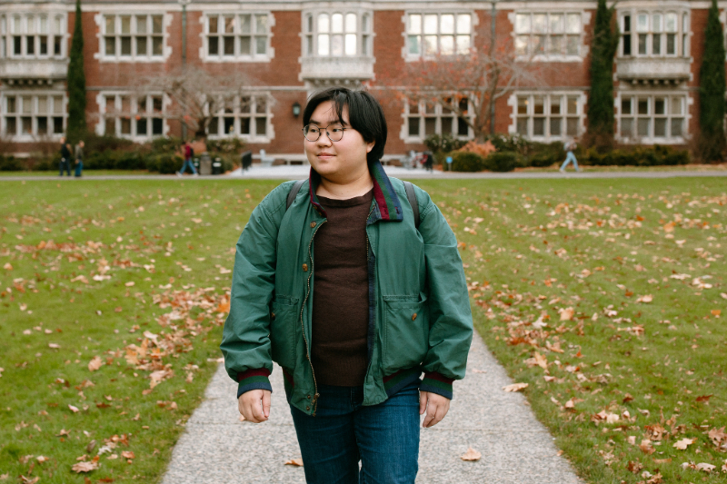 Student walking on campus and looking off in the distance
