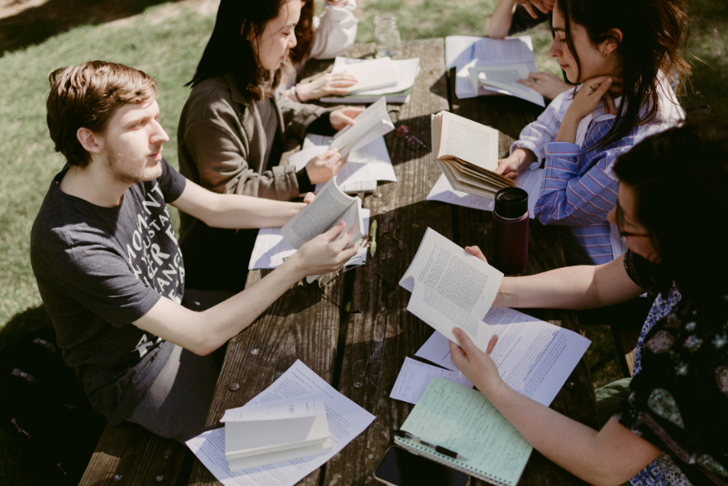 Group of students at a picnic table reading books and taking notes