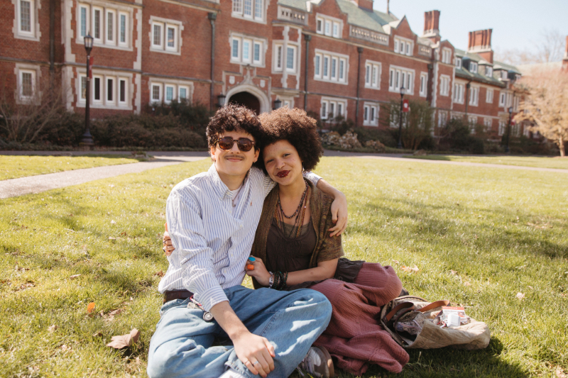 Two students hugging and smiling on the grass outside at Reed