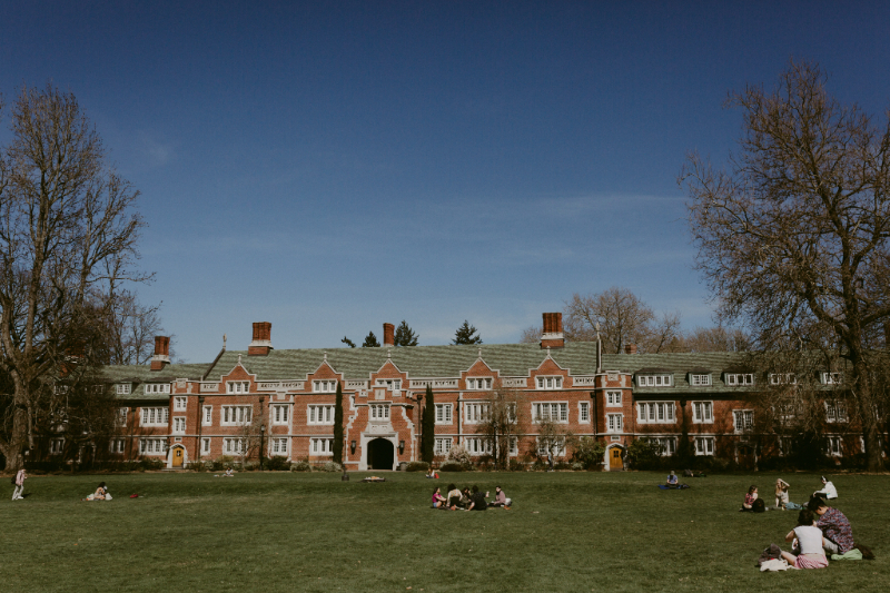 Numerous groups of students congregating outside on the grass at Reed