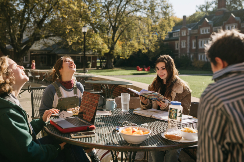 Four students eating and studying on a table outside at Reed