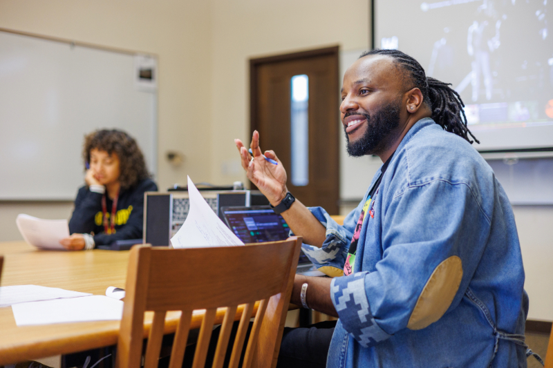 Dr. K holding a pen and smiling in a conference room
